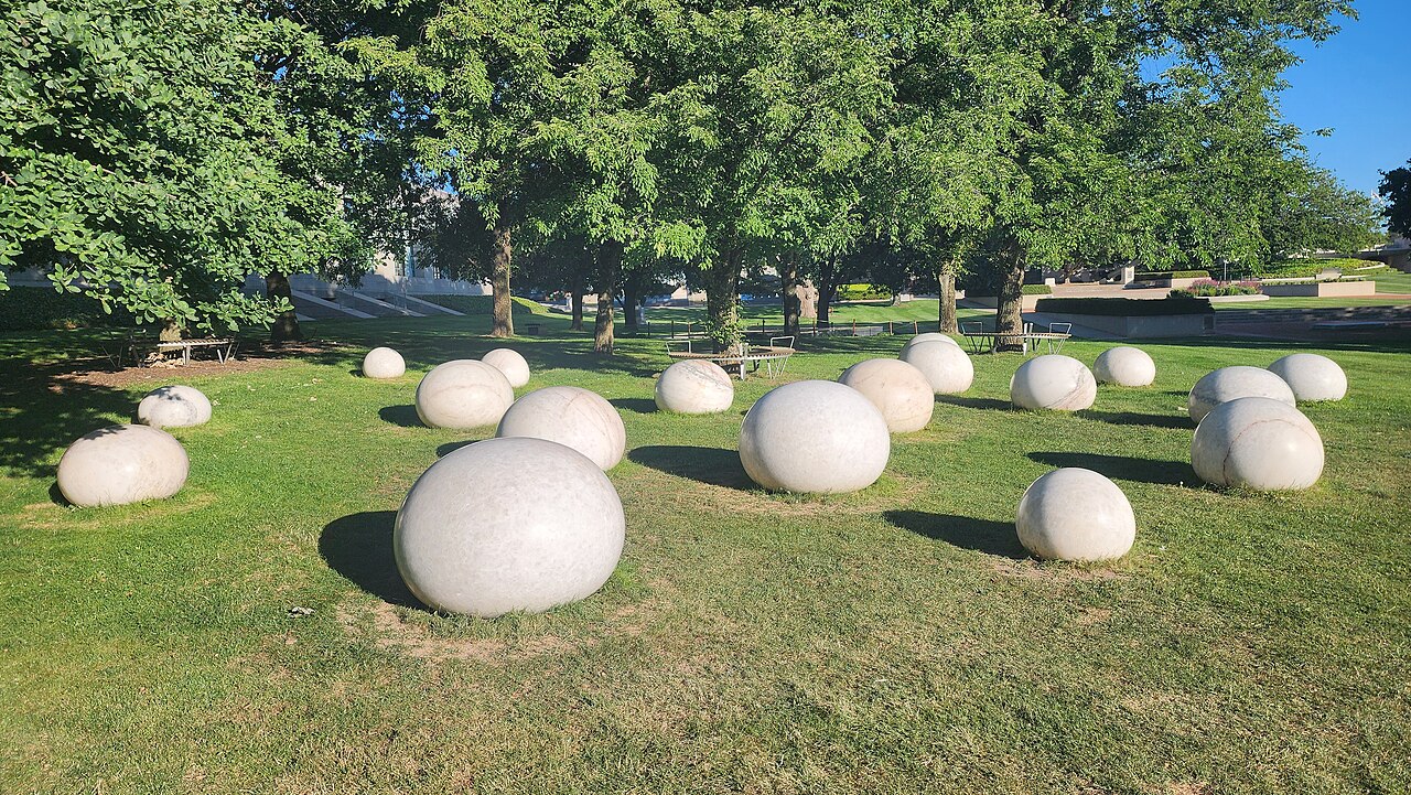 White marble droplet forms spread across a lawn in the Australian War Memorial Sculpture Garden.