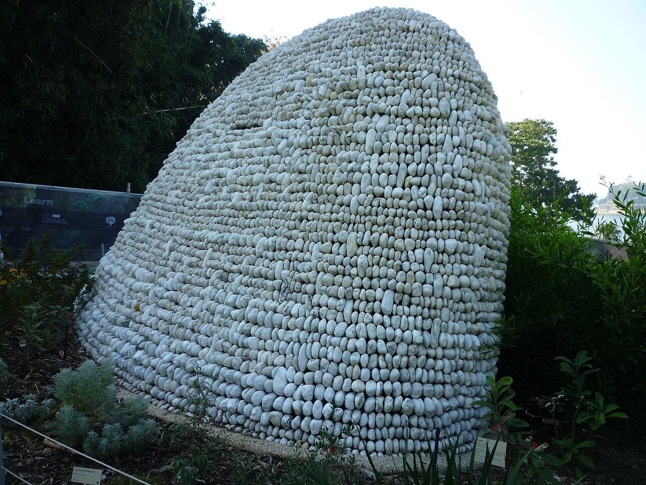 A monumental curved form built from rows of white quartz stones at the Royal Botanic Garden, Sydney.