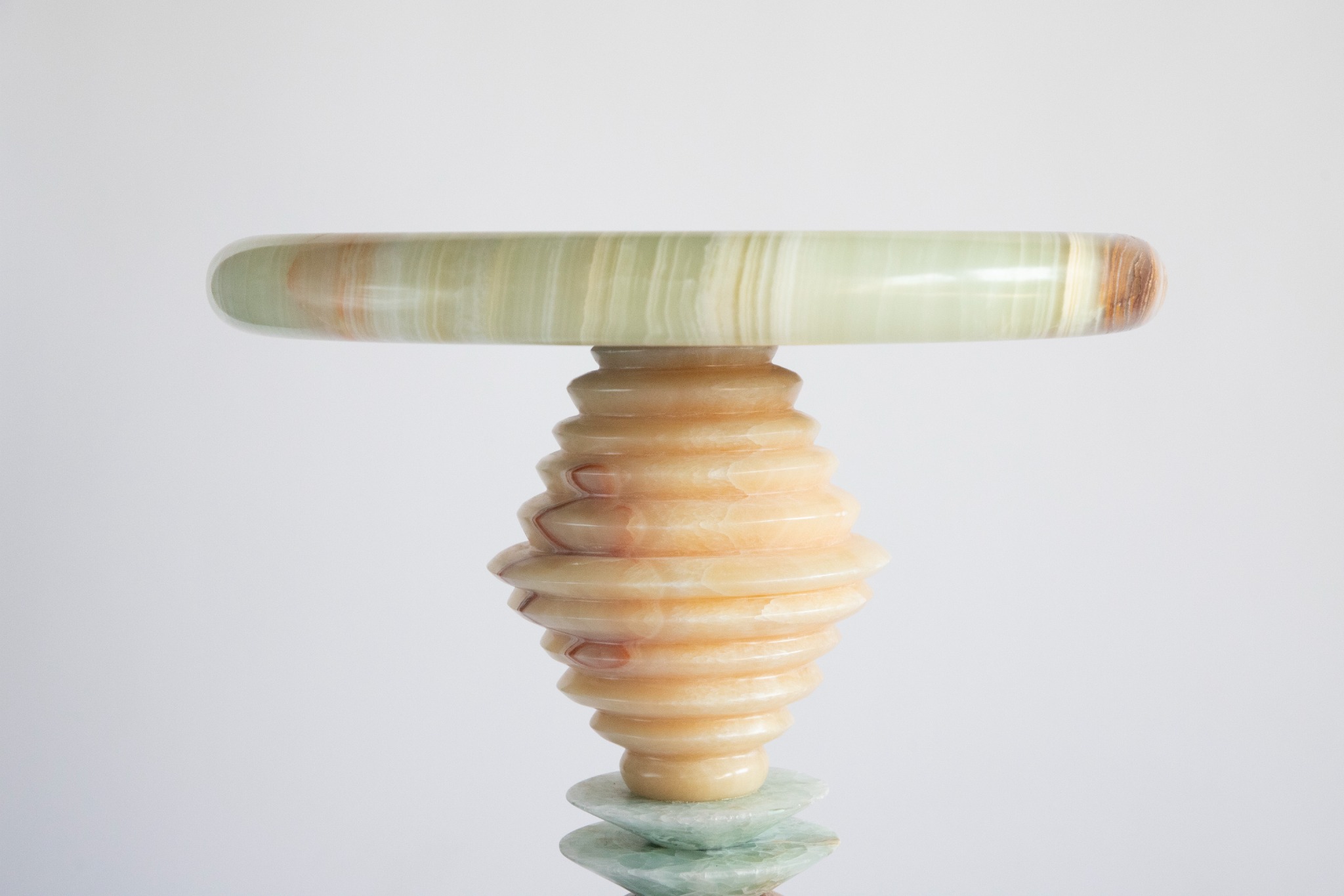 A close view of the pale green stone tabletop and ribbed amber-coloured stem of Cosmic Traces VII