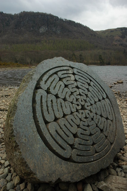 One carved half of Peter Randall-Page’s Hundred Year Stone beside Derwentwater, with concentric grooves across its cut face.