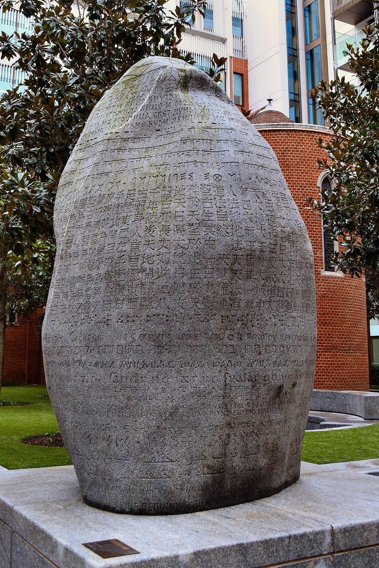 A tall granite boulder inscribed with scripts and symbols by Peter Randall-Page in Pearson Square, London.