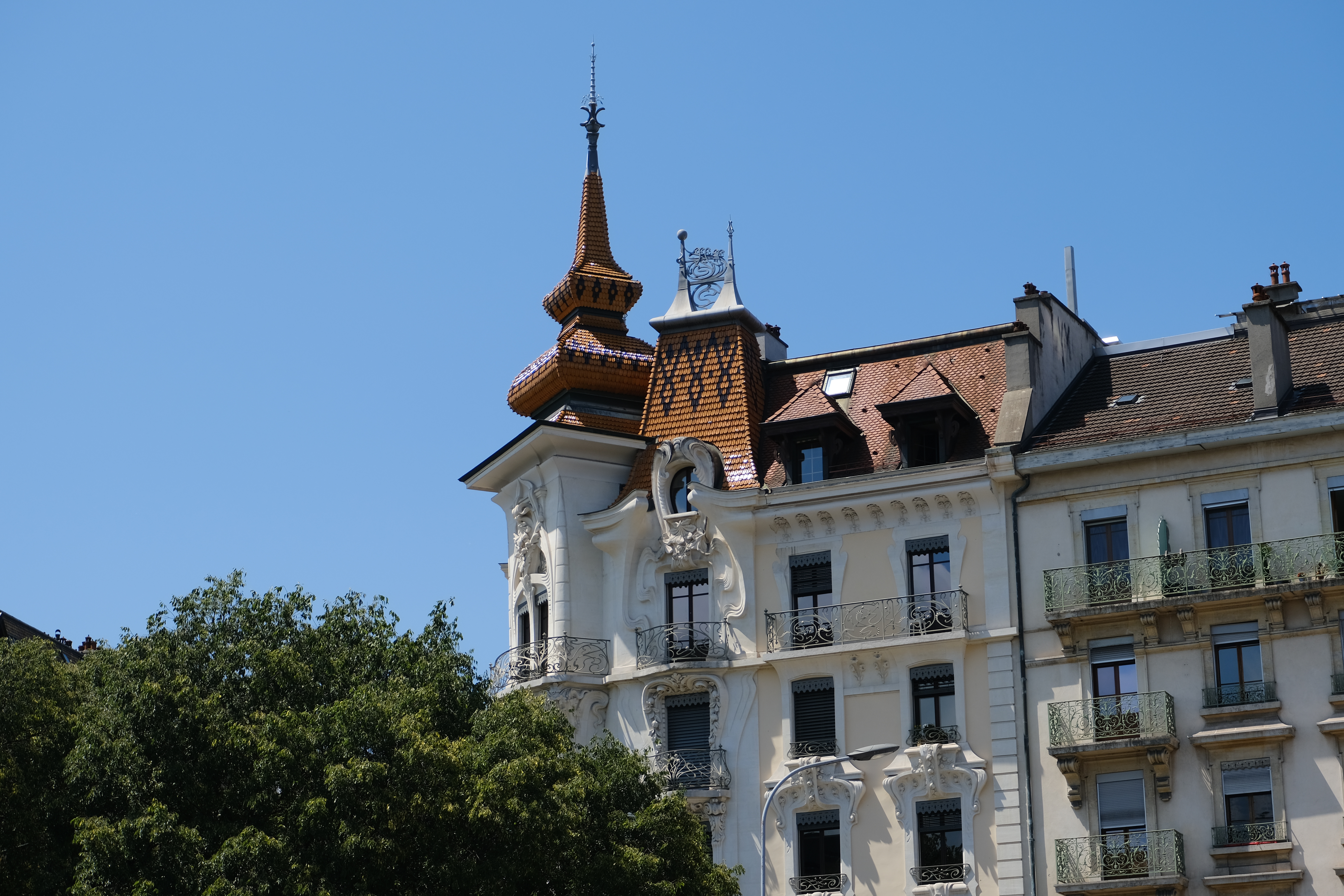 The stone facade, balconies, sculpted ornament and corner turret of the Maison des Paons in Geneva.